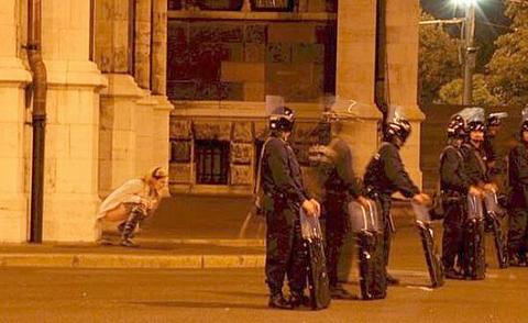 woman squatting to pee behind some riot cops